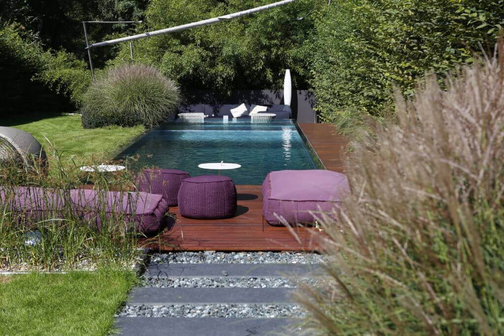 Edelstahlpool mit Holzdeck und stimmungsvoller Gartenbeleuchtung