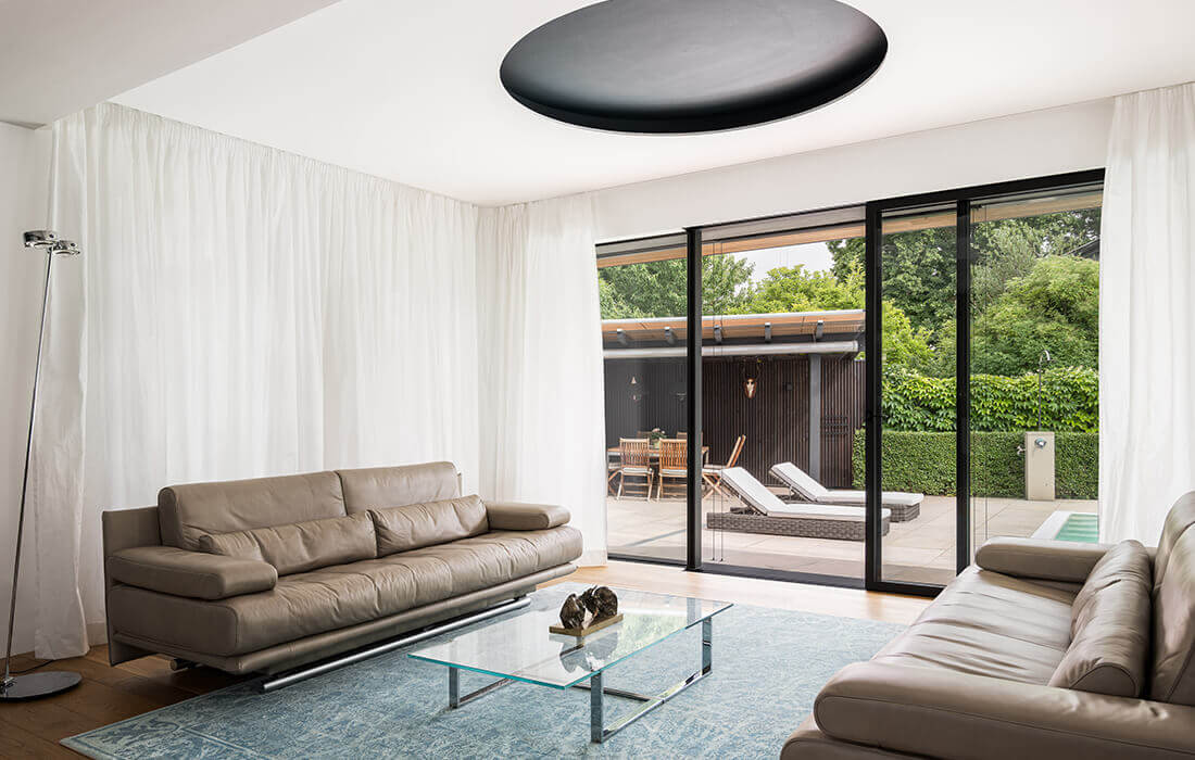 Blick durch Glasfront in einen stimmungsvoll beleuchteten Garten